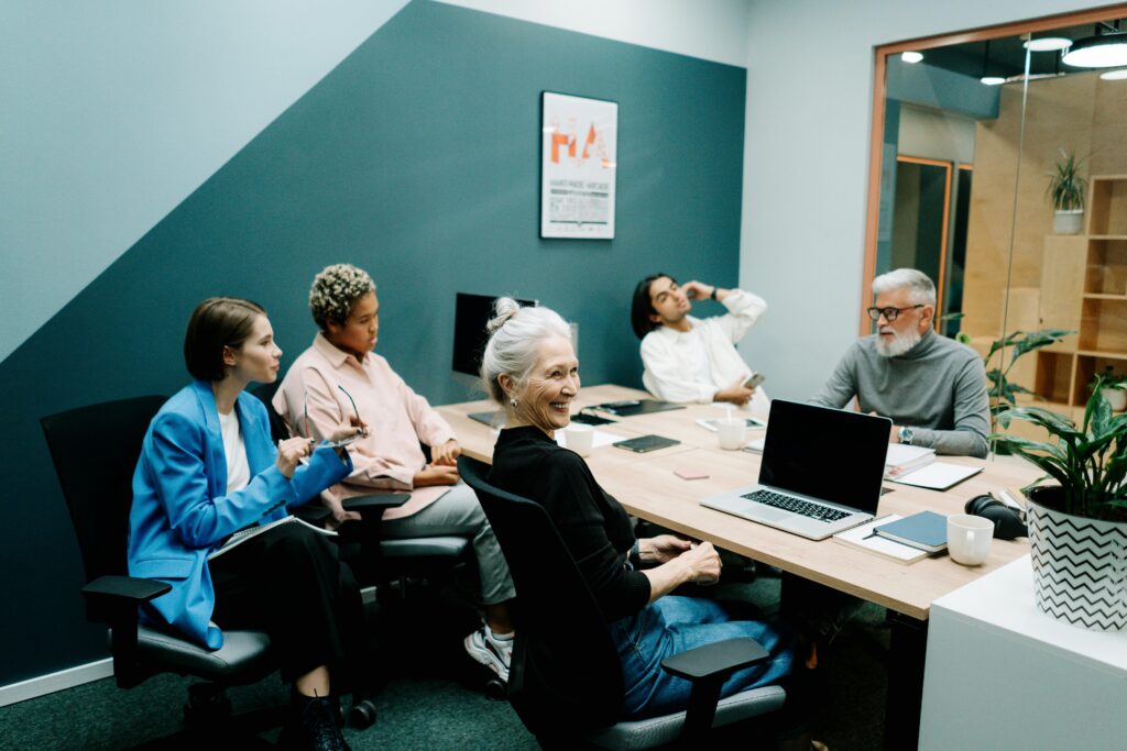 A diverse group of colleagues engaged in a meeting at a modern office, fostering teamwork and communication.