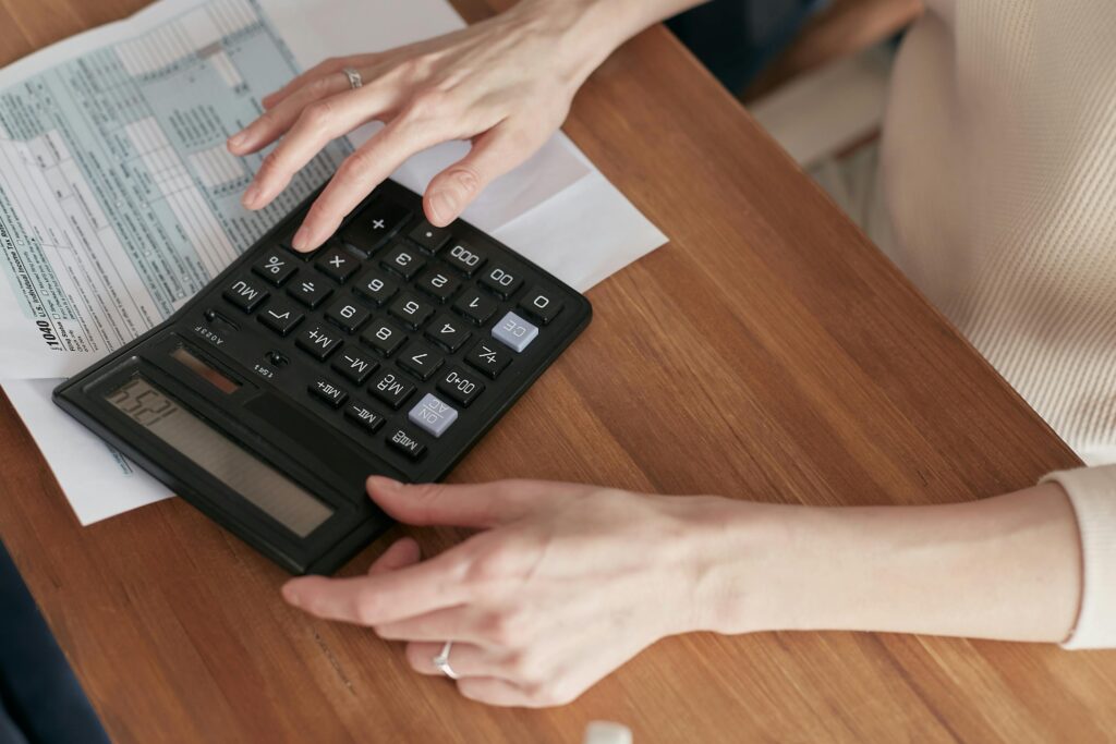 Close-up of a woman using a calculator and reviewing bills at home.