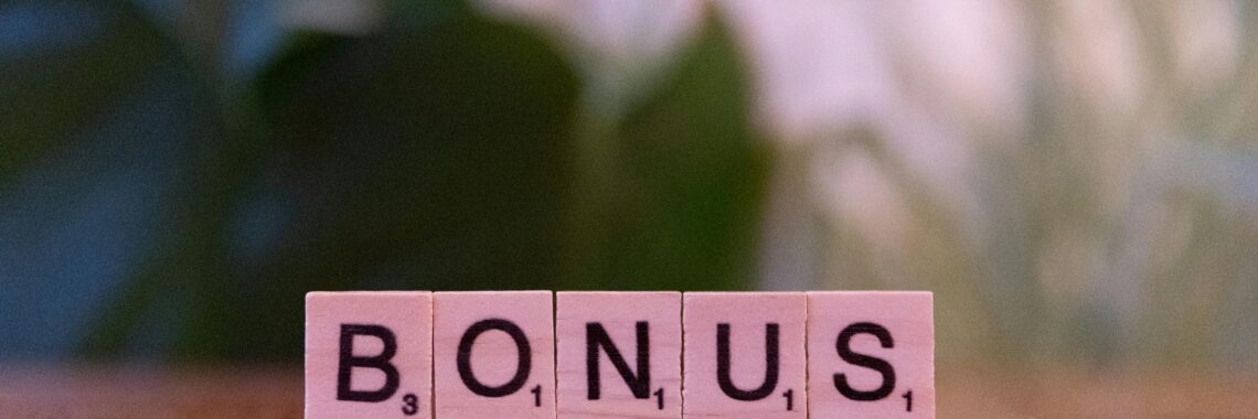 Close-up of the word BONUS spelled with Scrabble tiles on a table.
